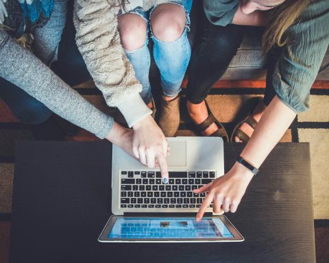 three person pointing the silver laptop computer