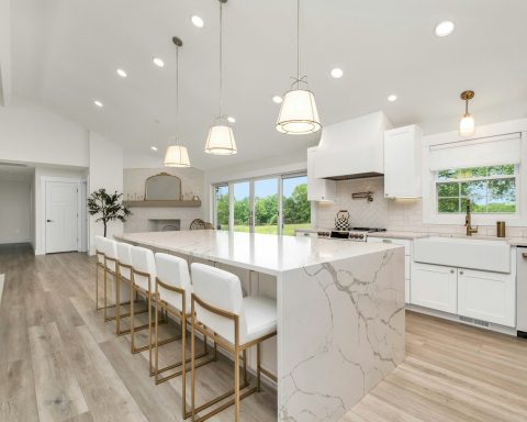 a large kitchen with a marble island and white cabinets