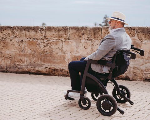 Oudere vrouw loopt buiten met een rollator op een stoep
